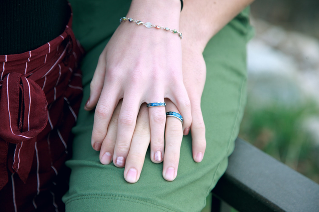 10 Nontraditional Wedding Gift Ideas for a Modern Couple, a couple holding hands and a clear view of their blue band wedding rings.